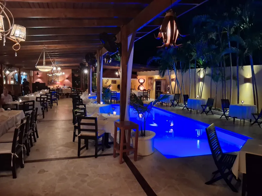 Bliss restaurant interior in Cabarete with elegant dining setup beside an illuminated blue pool at night