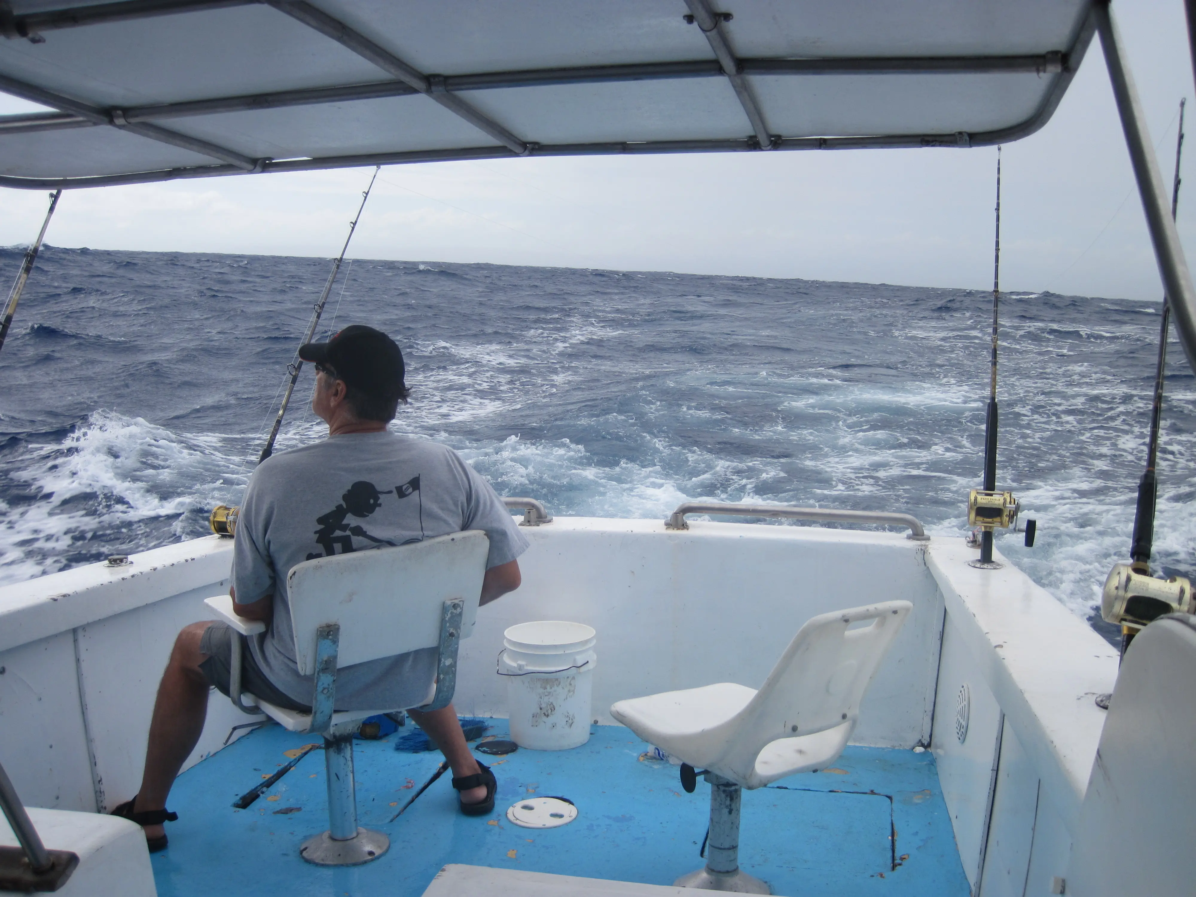 Angler seated on charter boat with fishing lines out on the open Atlantic off Sosúa
