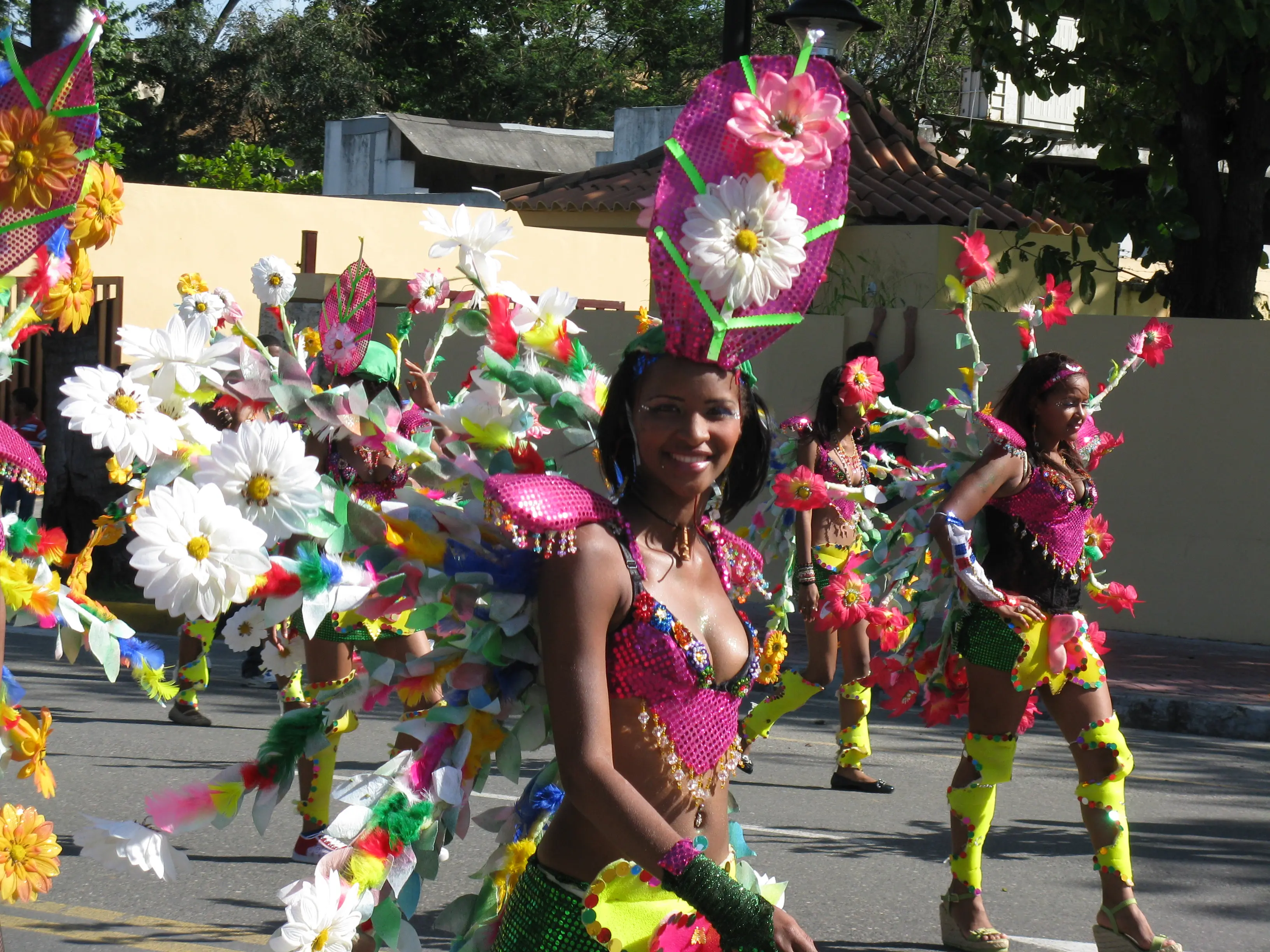 Carnaval dancers in elaborate pink and yellow flower costumes performing in the street