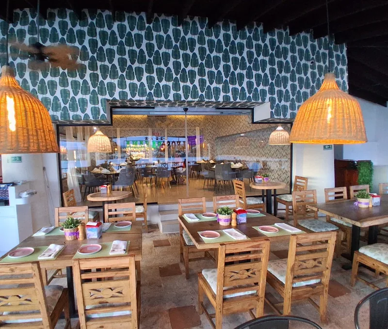 Dining room at Leo's Banana with wicker lamps and leaf wallpaper