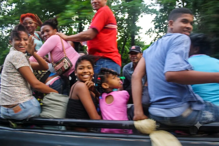 Smiling group of locals laughing together while riding in the back of a truck on a rural Dominican road