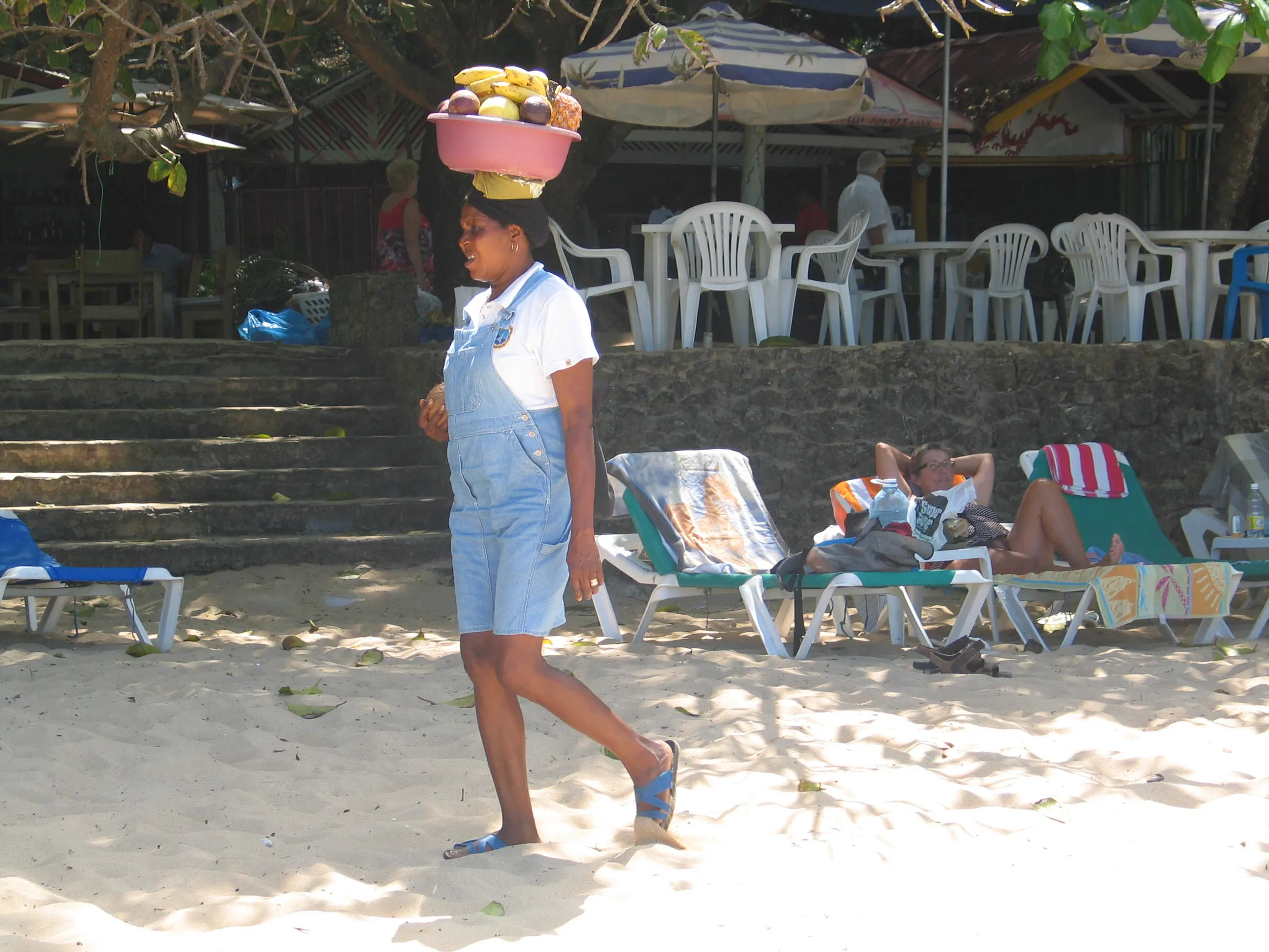 Local woman carrying a fruit basket on her head along Sosúa beach